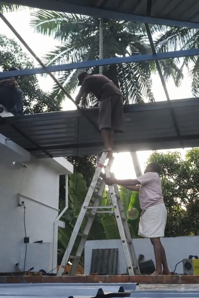 Worker cleaning roof sheet surface in Koyilandy
